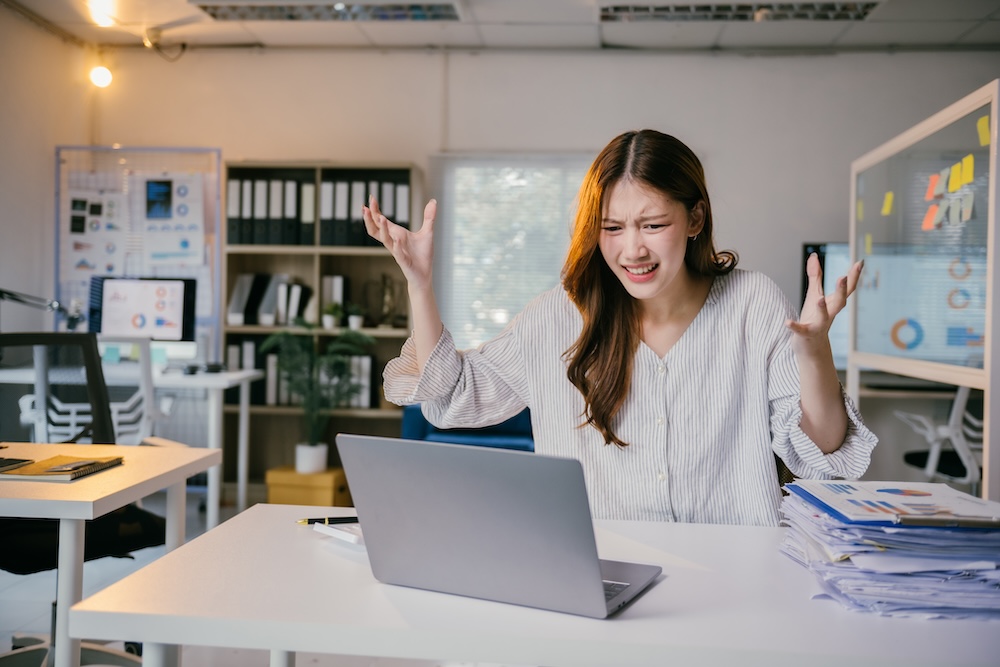Stressed businesswoman at desk, frustrated with laptop, overwhelmed by work pressure and errors, embodying challenges of small business owners