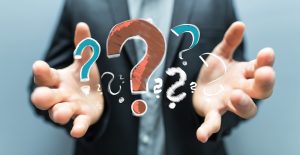 Man holding question marks in his hand. Concept of questions to ask before implementing AI.