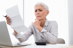 Business owner reviewing a bill at her laptop, puzzled by the hidden costs of AI sprawl and overlapping AI subscriptions